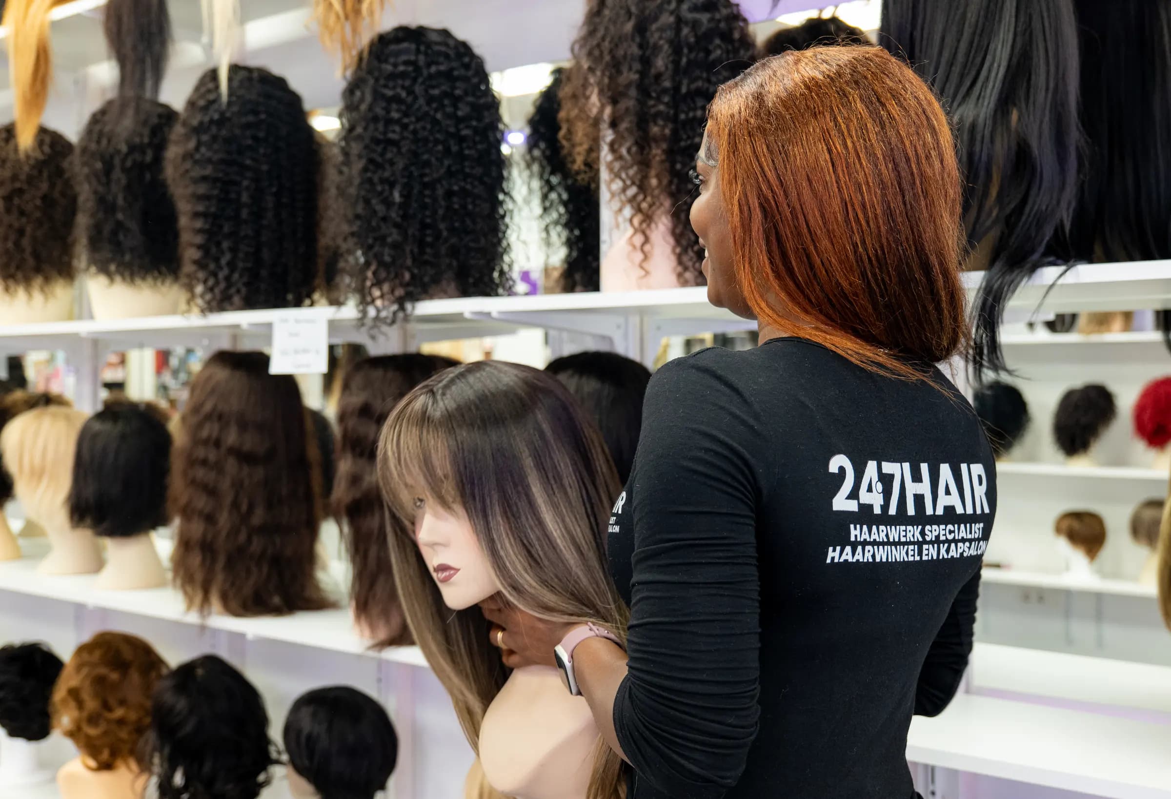 Medewerker van 247Hair bij de pruikenwand